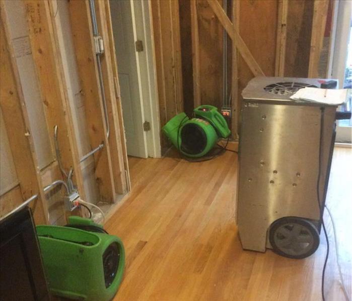 2 green air movers and a silver dehumidifier on a hardwood floor.