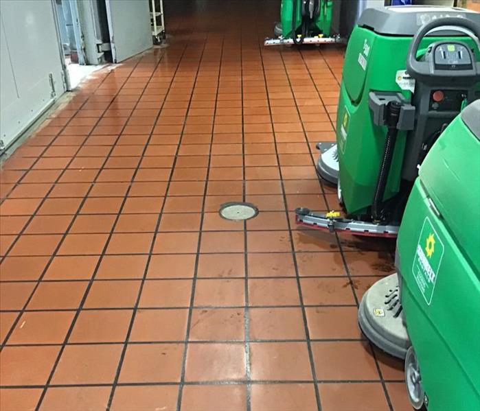 Two large green water extractors in a hallway on an orange tile floor