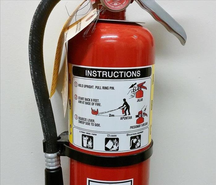 Red fire extinguisher with a black hose.