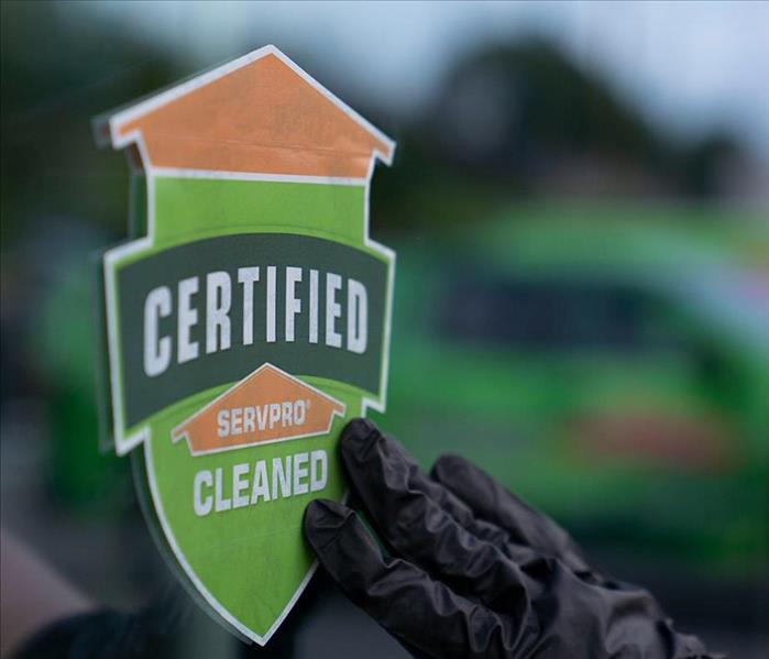 Certified: SERVPRO Cleaned sticker being placed on a glass door.