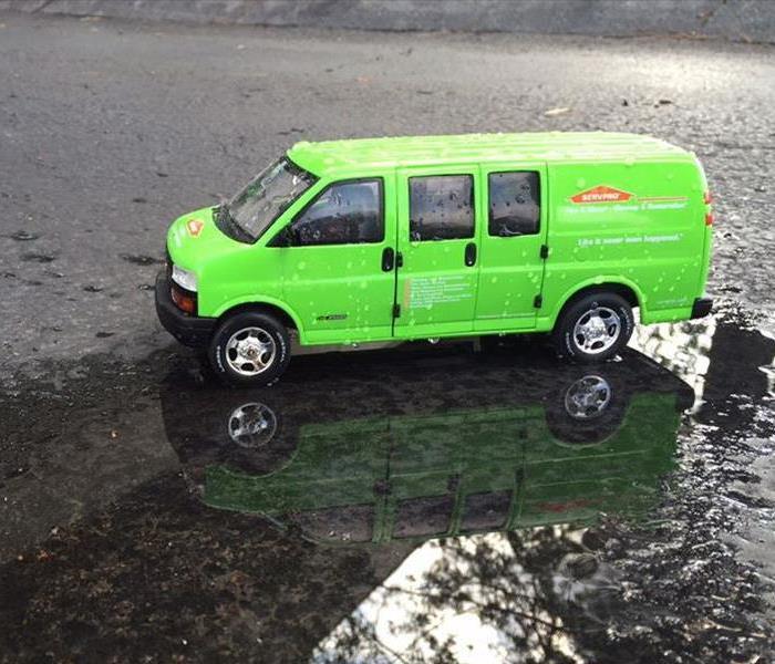 Green SERVPRO van on a wet street.