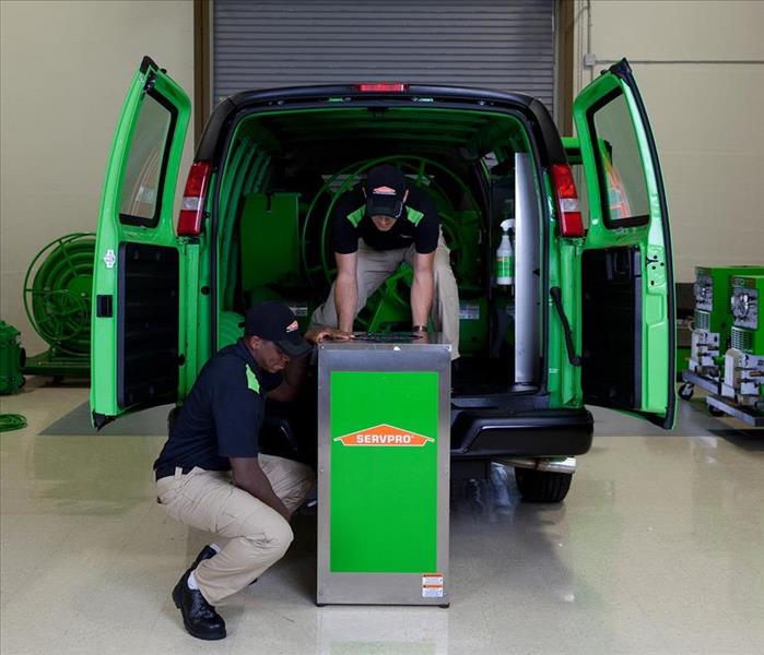 Two SERVPRO employees lifting a dehumidifier out of a van.