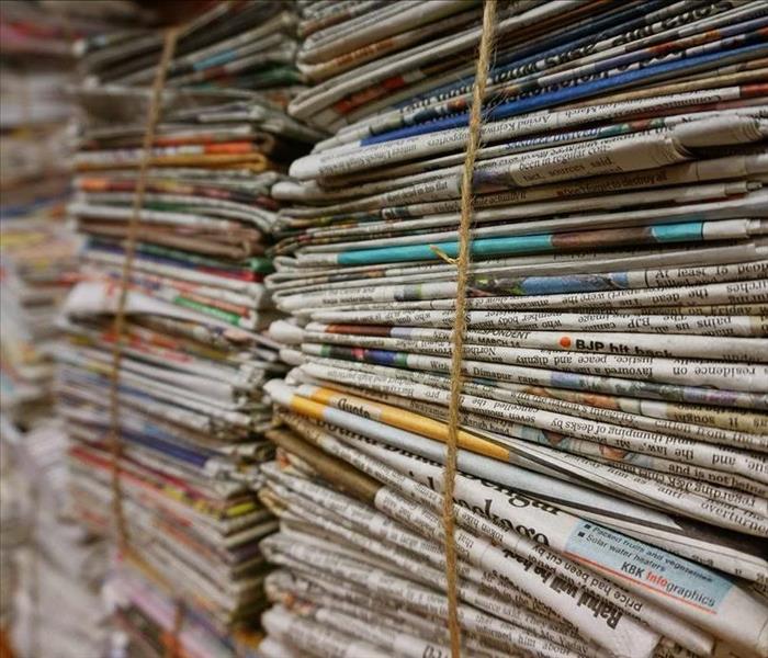 Stacks of newspapers bundled with a brown rope.