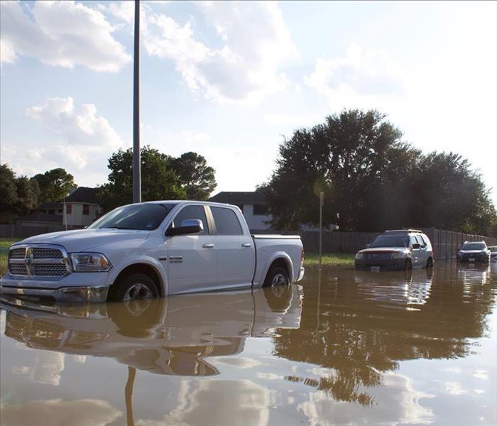 Flooded street with a white pickup truck up to the wheels in water.