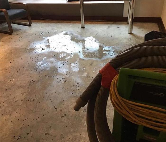 Wet concrete floor with SERVPRO equipment in the background.