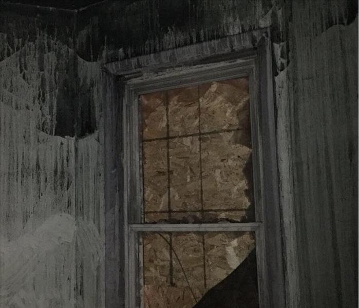 Soot covered room with a boarded up window.