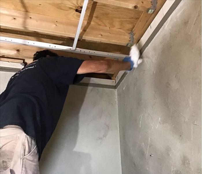 SERVPRO employee cleaning soot off of a wall.