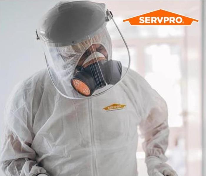 A SERVPRO employee in a white hazmat suit. 